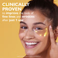 Woman wearing gold-colored gel eye patches under both eyes against a yellow background.