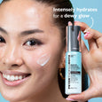 Clear hyaluronic serum bottle with gray cap held next to model's face showing dewy skin application.