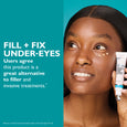 Woman holding white and blue tube of under-eye cream against turquoise background with product text.