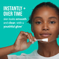 Woman holding white cotton swab applicator near her face against turquoise background.