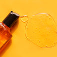 Clear orange gel cleanser in a bottle with black pump top, displayed with gel texture sample on yellow background.