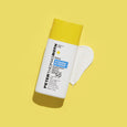 White sunscreen bottle with yellow cap and blue label beside white serum swatch on yellow background.