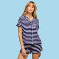 Woman wearing navy and white striped short-sleeve button-up pajama shirt and matching shorts set.
